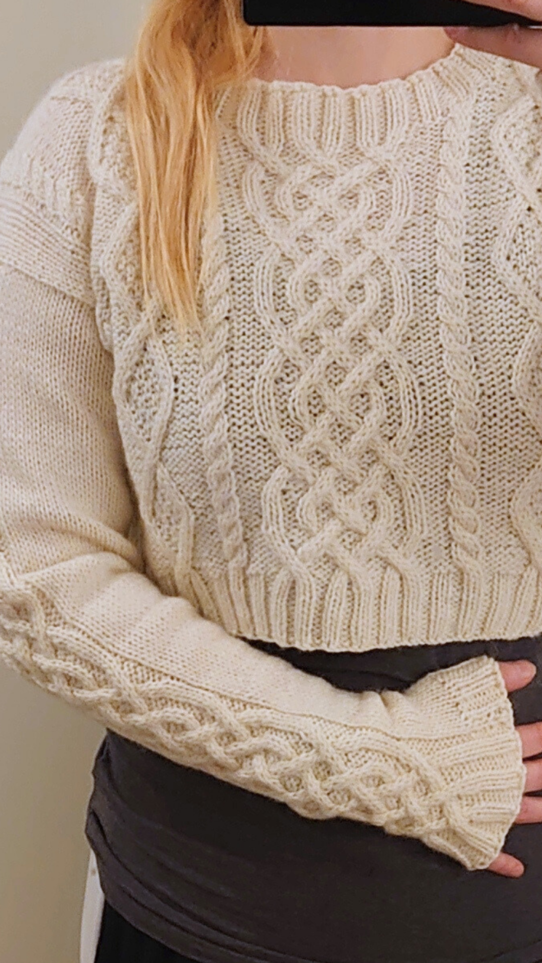 woman wearing hand knit cropped aran sweater with cables and overly long sleeves